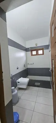 a bathroom with a toilet and a window in it at A cozy home bythe waterstream, tourist places near waynad in Kodenchery