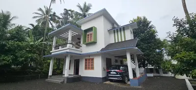 a white house with a car parked in front of it at A cozy home bythe waterstream, tourist places near waynad in Kodenchery