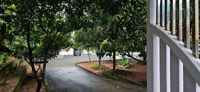 a white fence with trees on the side of a road at A cozy home bythe waterstream, tourist places near waynad in Kodenchery