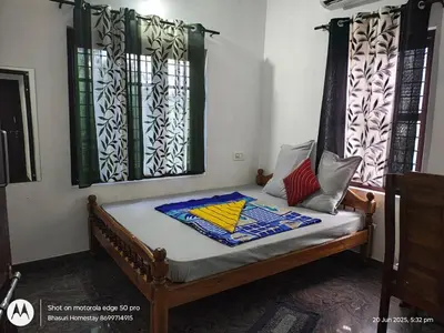 a bed in a room with two windows at Bhasuri AC Villa with Kitchen 1 in Agali