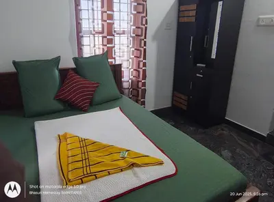 a green bed with a yellow robe on it at Bhasuri Non-AC Room in Agali