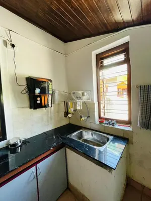 a kitchen with a sink and a window at Emnic Cottage Homestay in Meppādi