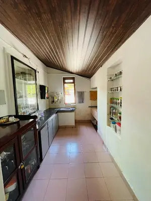 a kitchen with a wooden ceiling and a tile floor at Emnic Cottage Homestay in Meppādi