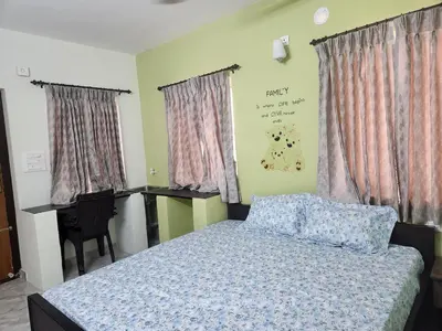 a bedroom with a bed and a desk and a chair at VPM Homestay in Coimbatore