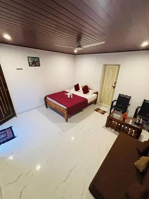 a bedroom with a bed and chairs in a room at Coorg Sunrise Cottage Homestay in Kushālnagar