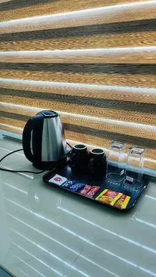 a tea kettle and cups on a tray on a table at LF Apartment in Kozhikode