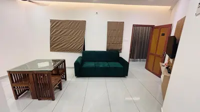 a living room with a green couch and a table at LF Apartment in Kozhikode