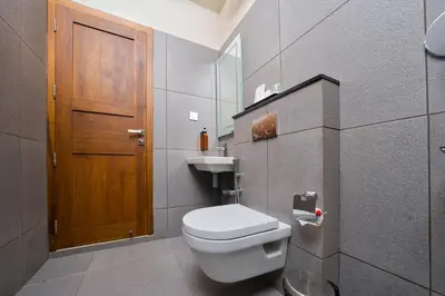 a bathroom with a toilet and a wooden door at MYSA Sky Suites, Lakkidi in Vythiri