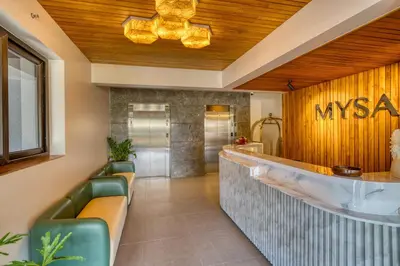 a lobby of a masyas restaurant with green chairs at MYSA Sky Suites, Lakkidi in Vythiri