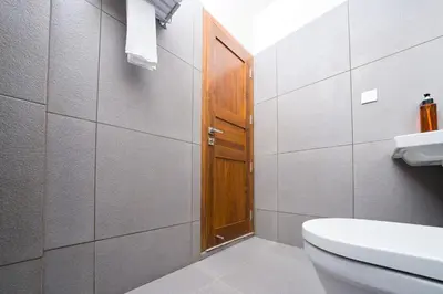 a bathroom with a toilet and a wooden door at MYSA Sky Suites, Lakkidi in Vythiri