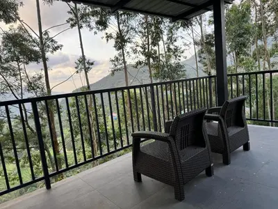 two chairs on a balcony with a view of a mountain at Honeyrock Farm Resort by Skybz in Kanthalloor