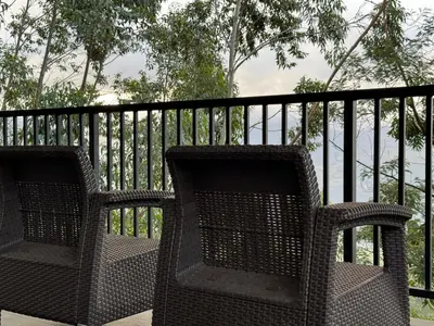 two wicker chairs sitting next to a black fence at Honeyrock Farm Resort by Skybz in Kanthalloor