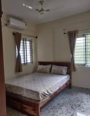 a bedroom with a bed and two windows at Sree Guruvayur Inn in Guruvāyūr