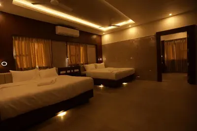 a hotel room with two beds and a couch at Arthana Residency Hotel