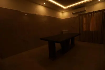 a dark room with a table and a toilet at Arthana Residency Hotel