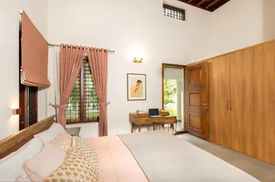 a bedroom with a bed and a desk and a window at Eka in Kodungallūr
