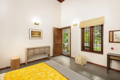 a bedroom with a bed and a table and a window at Eka in Kodungallūr