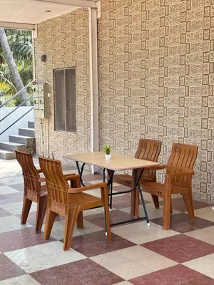 a wooden table and chairs on a patio at Hamsa Farmstay Mysore, Campfire, Bbq, Cricket in Mysore