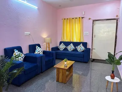 a living room with two blue couches and a table at Hamsa Farmstay Mysore, Campfire, Bbq, Cricket in Mysore