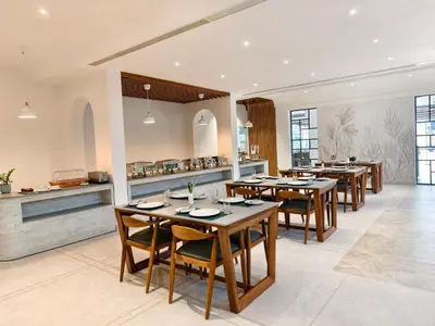 a restaurant with wooden tables and chairs and a counter at CASTELO Inn in Nedumbassery