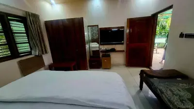 a bedroom with a bed and a tv in it at NesaraVana - Ecostay in Hārohalli