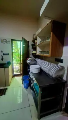 a kitchen with stacks of white plates on a counter at NesaraVana - Ecostay in Hārohalli