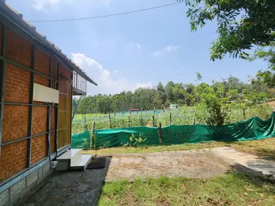 a building with a fence in front of a field at Tusker Valley Bamboo Room Mudumalai by Privacy Homes in Mudumalai National Park