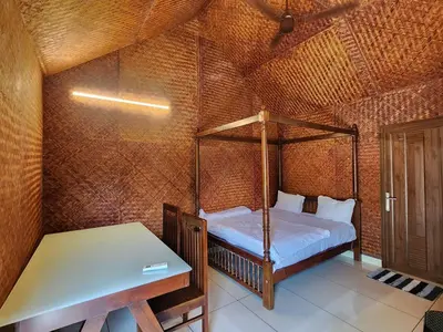a bedroom with a bed and a table in a room at Tusker Valley Bamboo Room Mudumalai by Privacy Homes in Mudumalai National Park