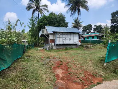 a small house in a field next to a fence at Tusker Valley Bamboo Room Mudumalai by Privacy Homes in Mudumalai National Park