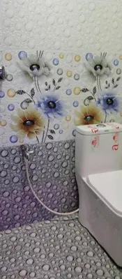 a bathroom with a toilet with flowers on the wall at Misty plaza in Vattavada