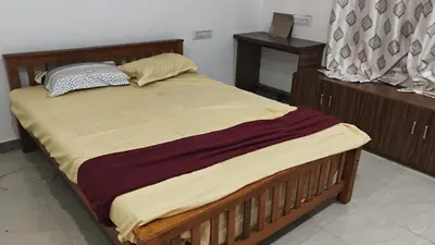 a bedroom with a large bed with a wooden frame at Johnnys Destination in Angamali