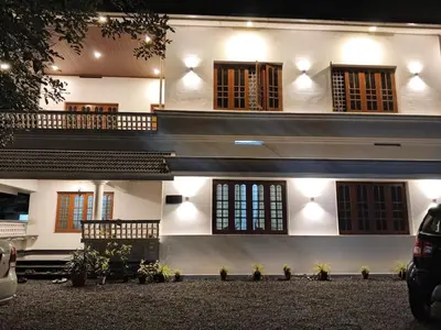 a white building with windows and a lot of plants at Johnnys Destination in Angamali