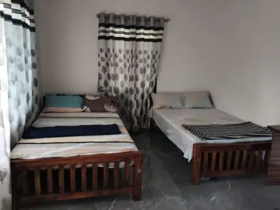 two twin beds in a room with curtains at Johnnys Destination in Angamali