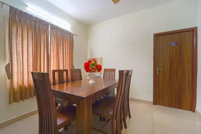 a dining room table with chairs and a vase of flowers at Chakraa Hotels in Coimbatore