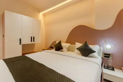 a bedroom with a large white bed with black pillows at Legacy Inn, Mysore in Mysore
