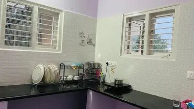 a kitchen with a black counter top and two windows at Mysore Stopover in Mysore