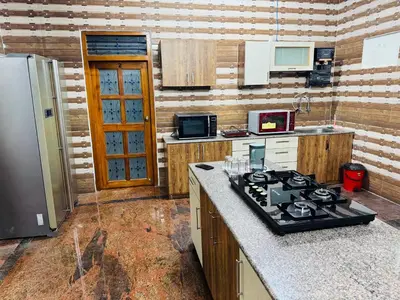 a kitchen with a stove and a refrigerator at LUXE Penthouse 4BHK with Swimming pool in Mysore