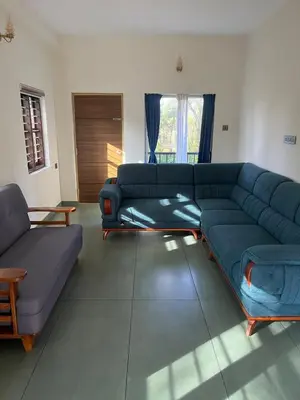 a living room with a blue couch and a table at Farmscape Retreat in Gonikoppal