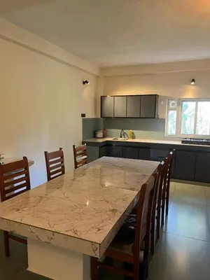 a kitchen with a large marble table and chairs at Farmscape Retreat in Gonikoppal