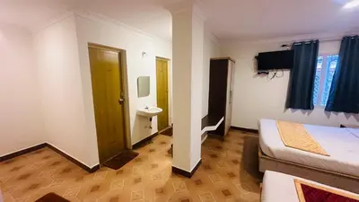 a small room with a bed and a bathroom at VR Residency in Ooty