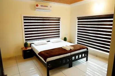 a bedroom with a bed in a room with two windows at Daya Village in Tirūrangādi