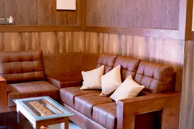 a brown leather couch in a room with a table at Daya Village in Tirūrangādi