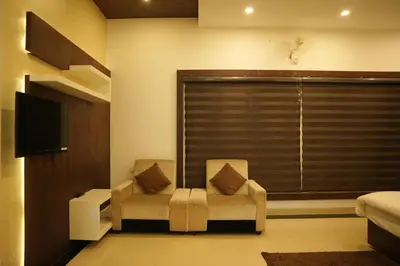 a bedroom with a bed and a chair and a television at The Glen By Bloobuck in Ambalavayal