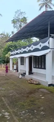 a white house with a black and white roof at ARAVON Homes in Meenangadi