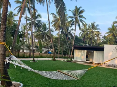 a hammock hanging from a palm tree in front of a building at Reflections by SOL Escapes near Cherai Beach in Pallipuram