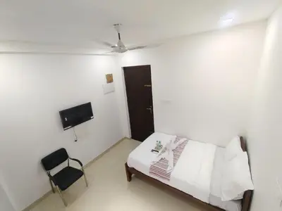 a bedroom with a bed and a chair in it at Goldwins Grand A comfort stay in Coimbatore