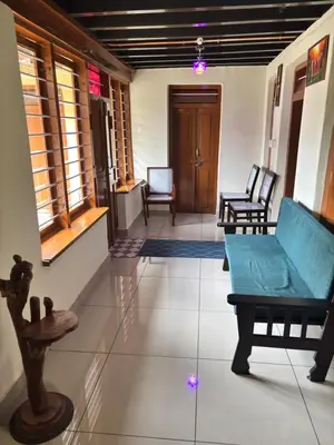 a living room with a blue couch and chairs at KODIYADAN s INN A Homestay with a Heart in Meenangadi
