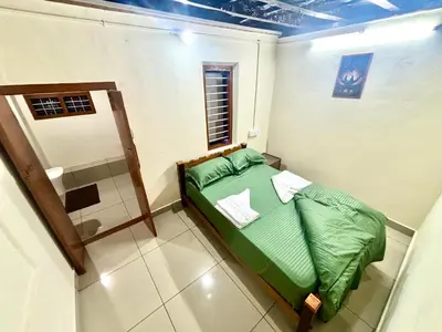 a small bedroom with a green bed and a window at KODIYADAN s INN A Homestay with a Heart in Meenangadi