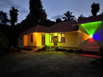 a house lit up at night with a rainbow at KODIYADAN s INN A Homestay with a Heart in Meenangadi