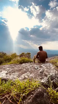 a man sitting on a rock looking at the view at Wayanad Camping in Ambalavayal